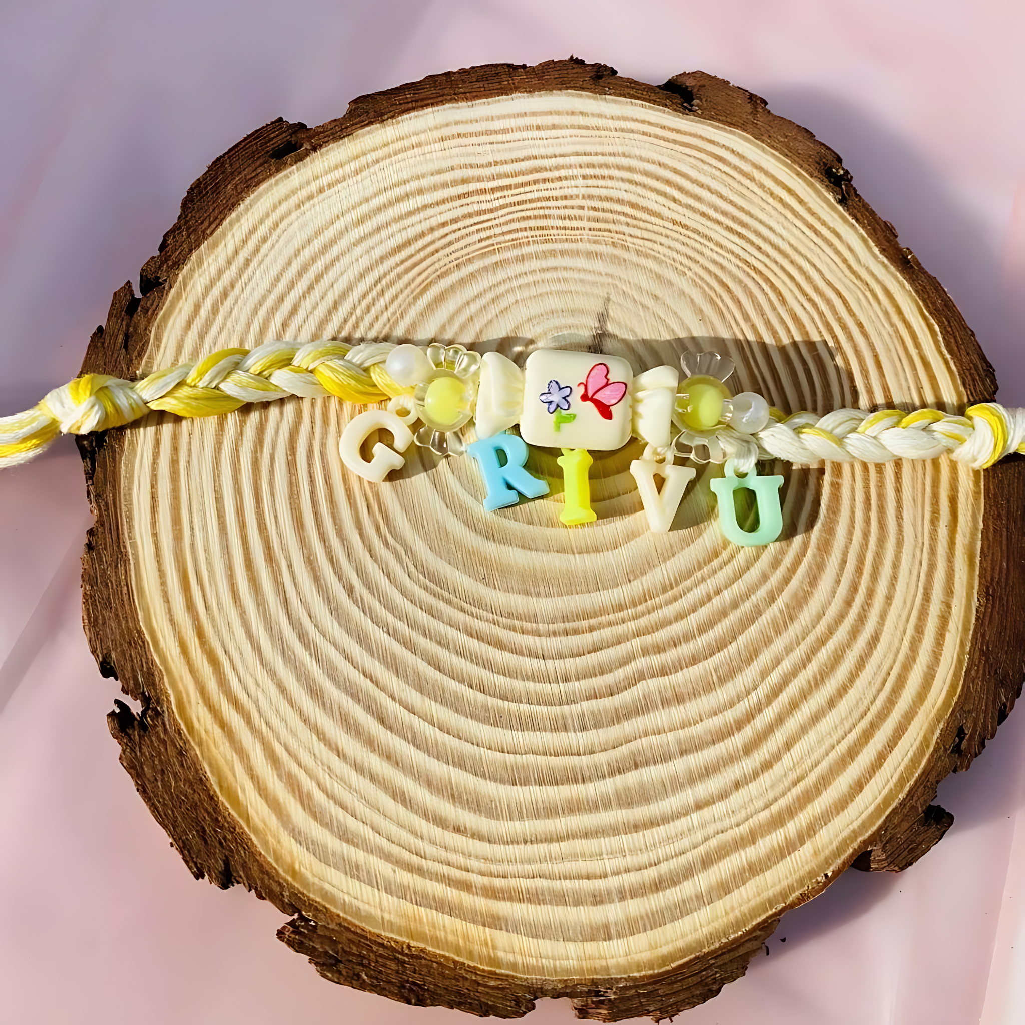 Cute pastel-colored name Rakhi for kids with yellow-white braided thread