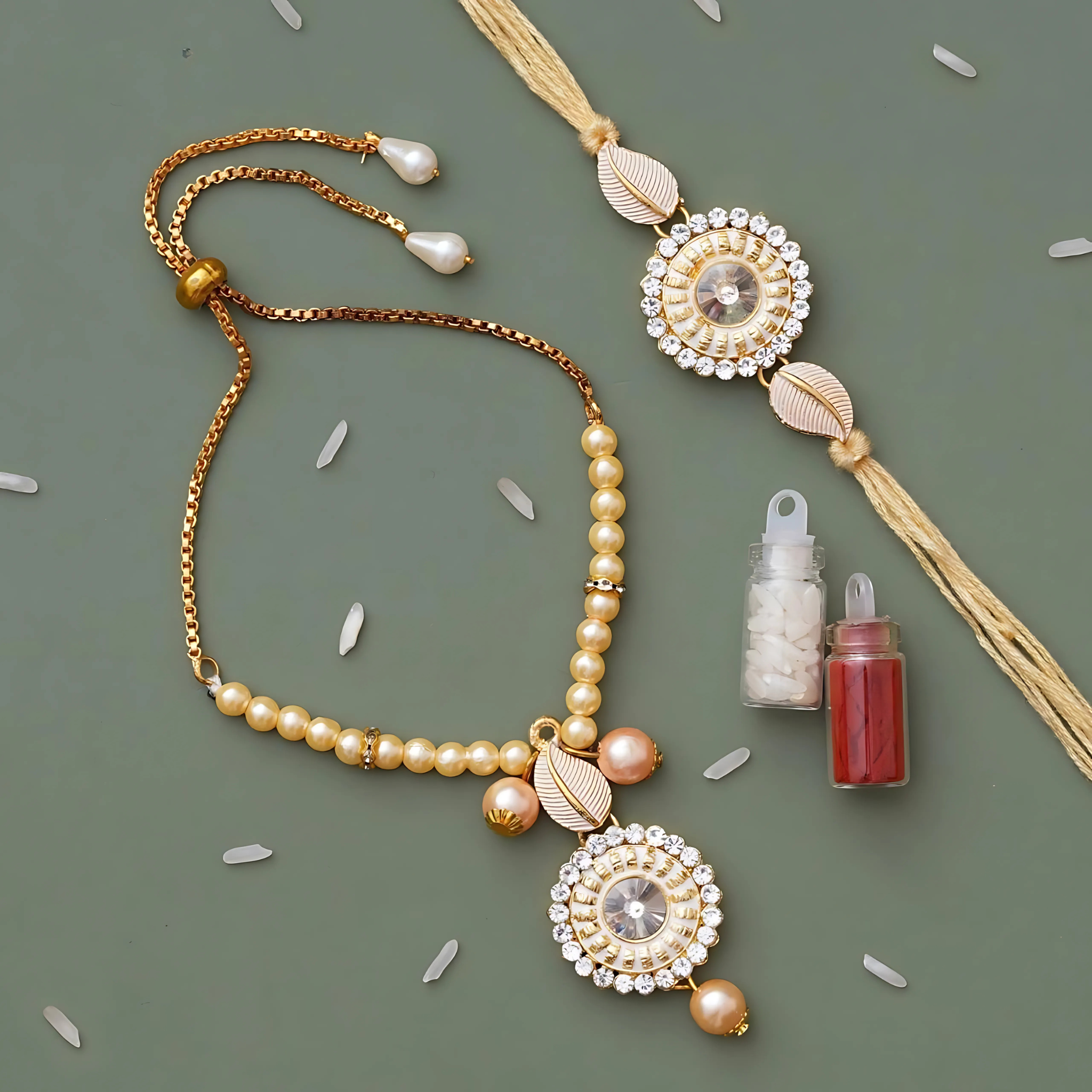 Premium Bhaiya Bhabhi Rakhi set with matching pearl Lumba bracelet, round crystal centerpiece, golden leaf detailing, and Roli-Chawal containers – displayed on green background.